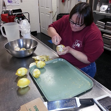 Woman in a TCRC shirt zests and peels lemons.